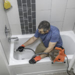 Drain Cleaning by Plumber Drain Cleaning A Bathtub With A Plumbers Snake